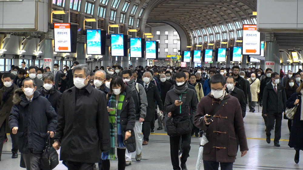 Menschenmenge im Bahnhof Shinagawa in der Rushhour mit Maske.