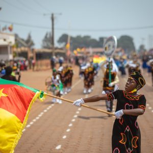 Eine Frau schwenkt auf einer Parade die kamerunische Flagge