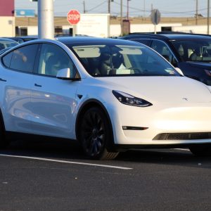 Weißer Tesla auf Neuwagen-Parkplatz.