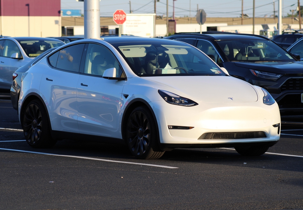 Weißer Tesla auf Neuwagen-Parkplatz.