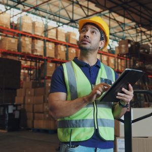 Arbeiter mit Helm und Tablet im Lager